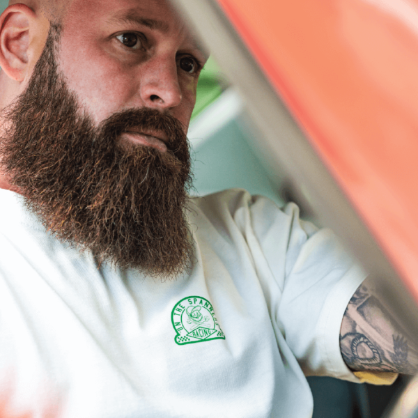 Toolbox Tee in Bone being modelled by a mechanic. T-shirt sizes M, L, XL, XXL